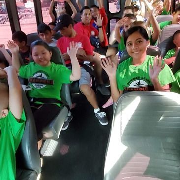 A group of children on a bus wearing green shirts that say power camp