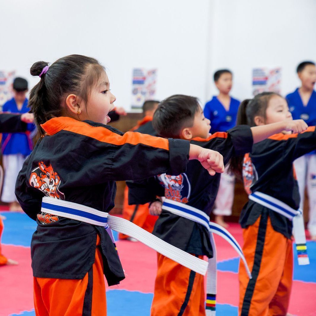 A group of children are practicing martial arts in a gym