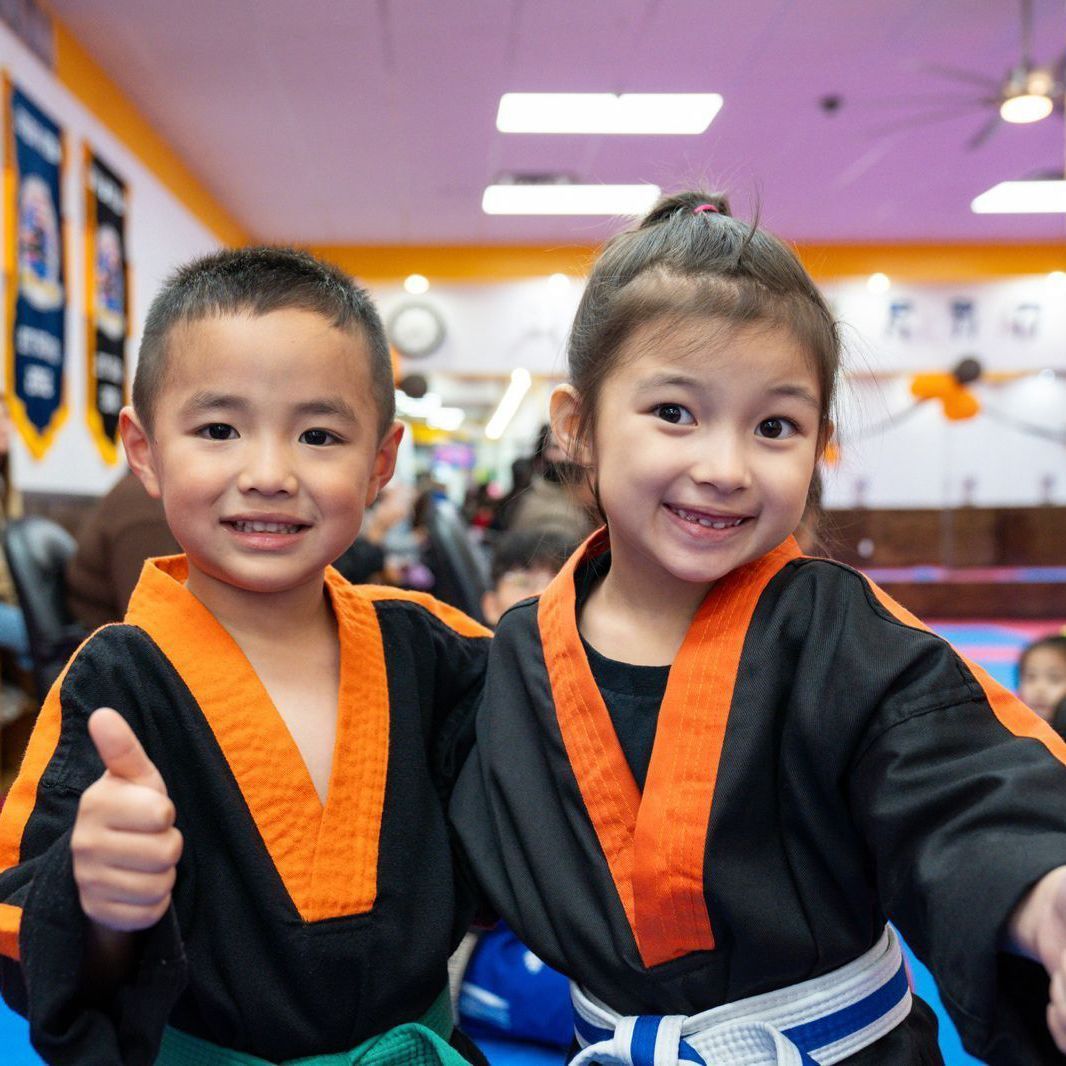 A boy and a girl are posing for a picture and the girl is giving a thumbs up