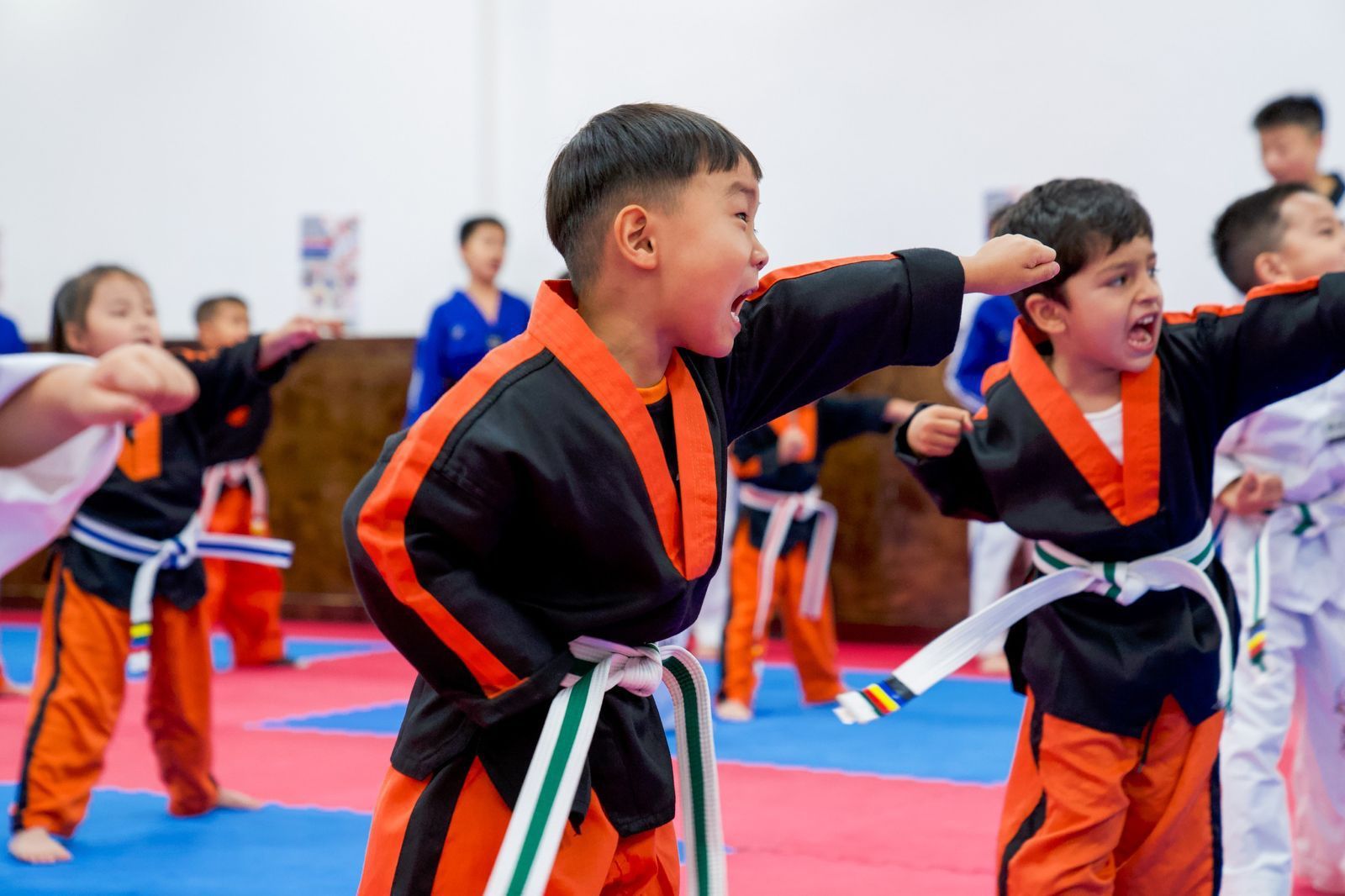 A group of young boys are practicing martial arts in a gym.