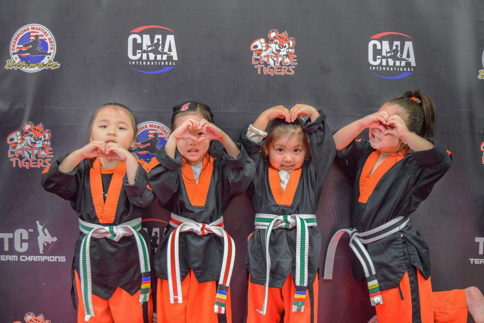 A group of young girls are making a heart shape with their hands.