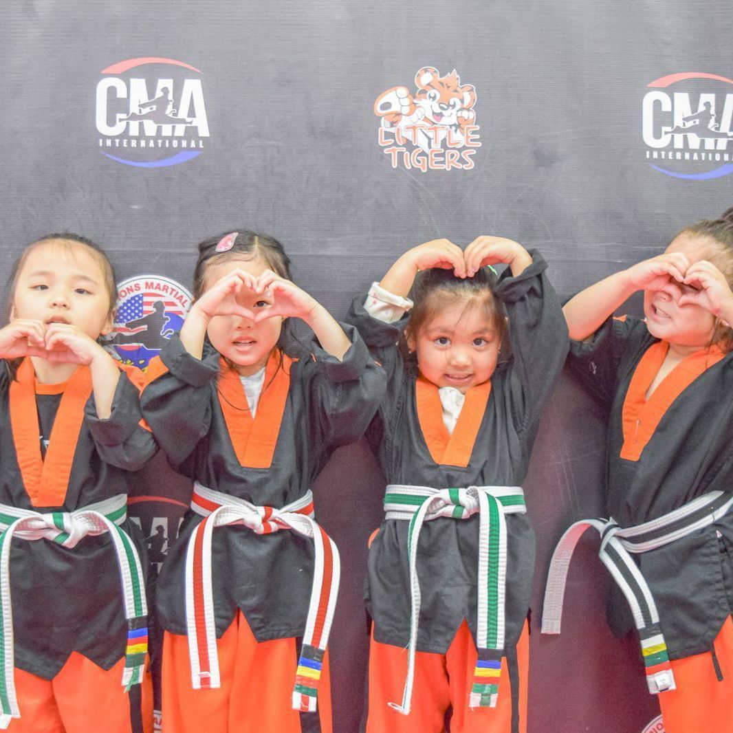 A group of young girls are making a heart shape with their hands