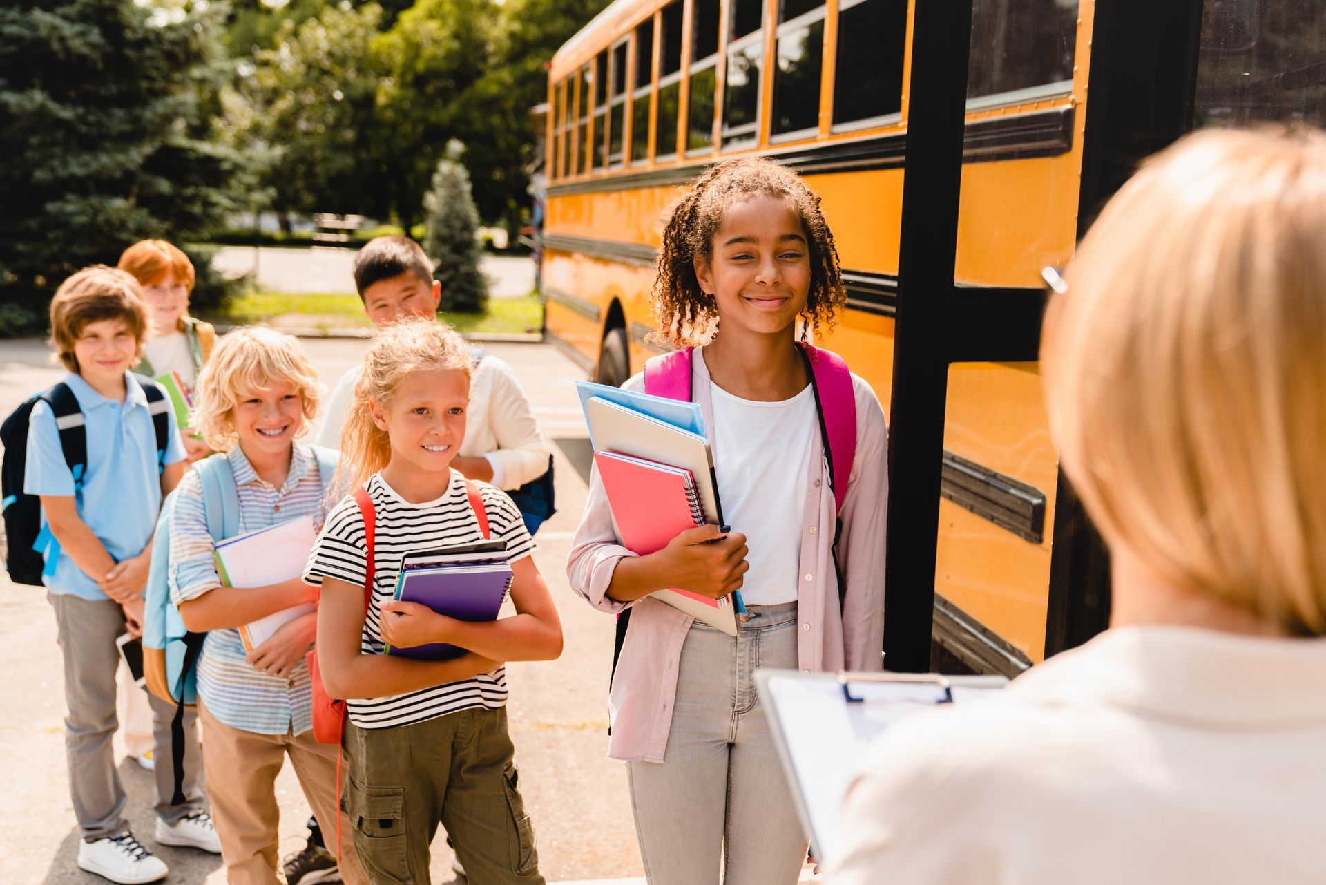 A group of children are standing in line to get on a school bus.