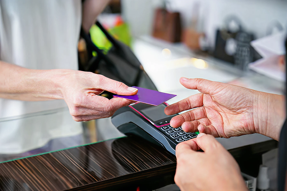Handing a purple card to a cashier at a payment terminal