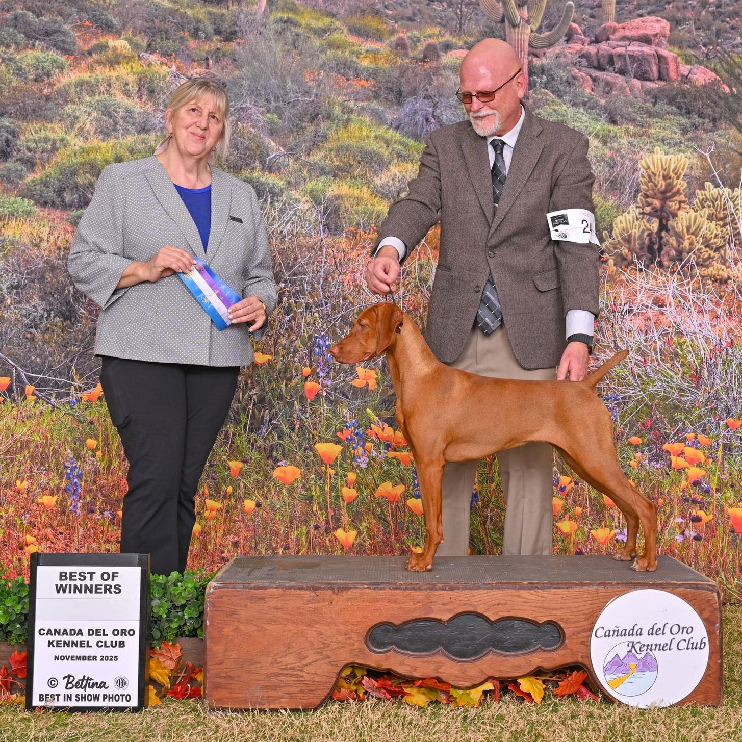 Two women standing next to a dog with a sign that says lost dutchman kennel club february 2018
