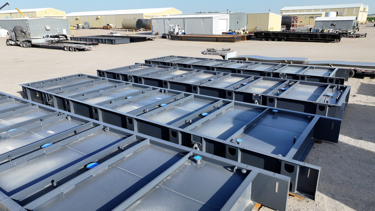 Rows of gray metal rectangular structures sit outdoors, possibly for construction or storage.