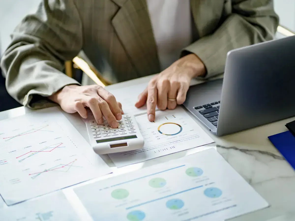 Gemini said A professional uses a calculator and laptop to perform a detailed gross profit analysis.