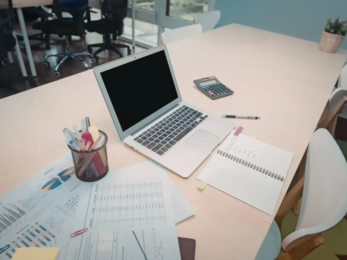 Office desk with a laptop, calculator, and reports showing a gross profit analysis.