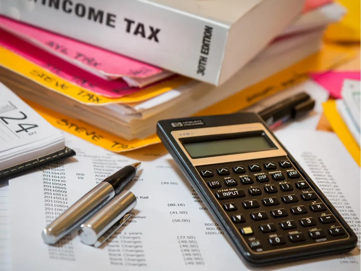 Tax papers and calculator showing the need to hire a bookkeeper.