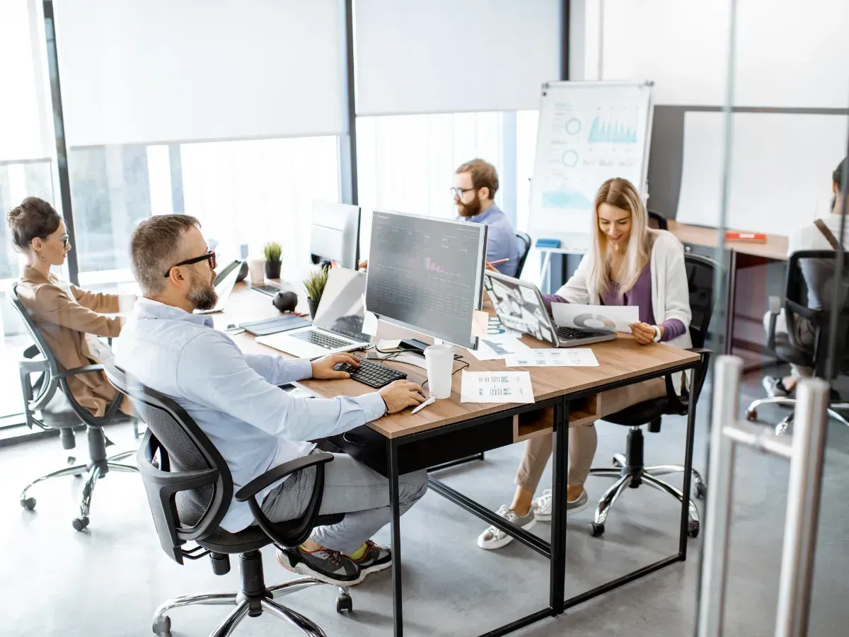 Team of professionals in a modern office working on reports and technology, showing the benefits of outsourcing direct bill processing.