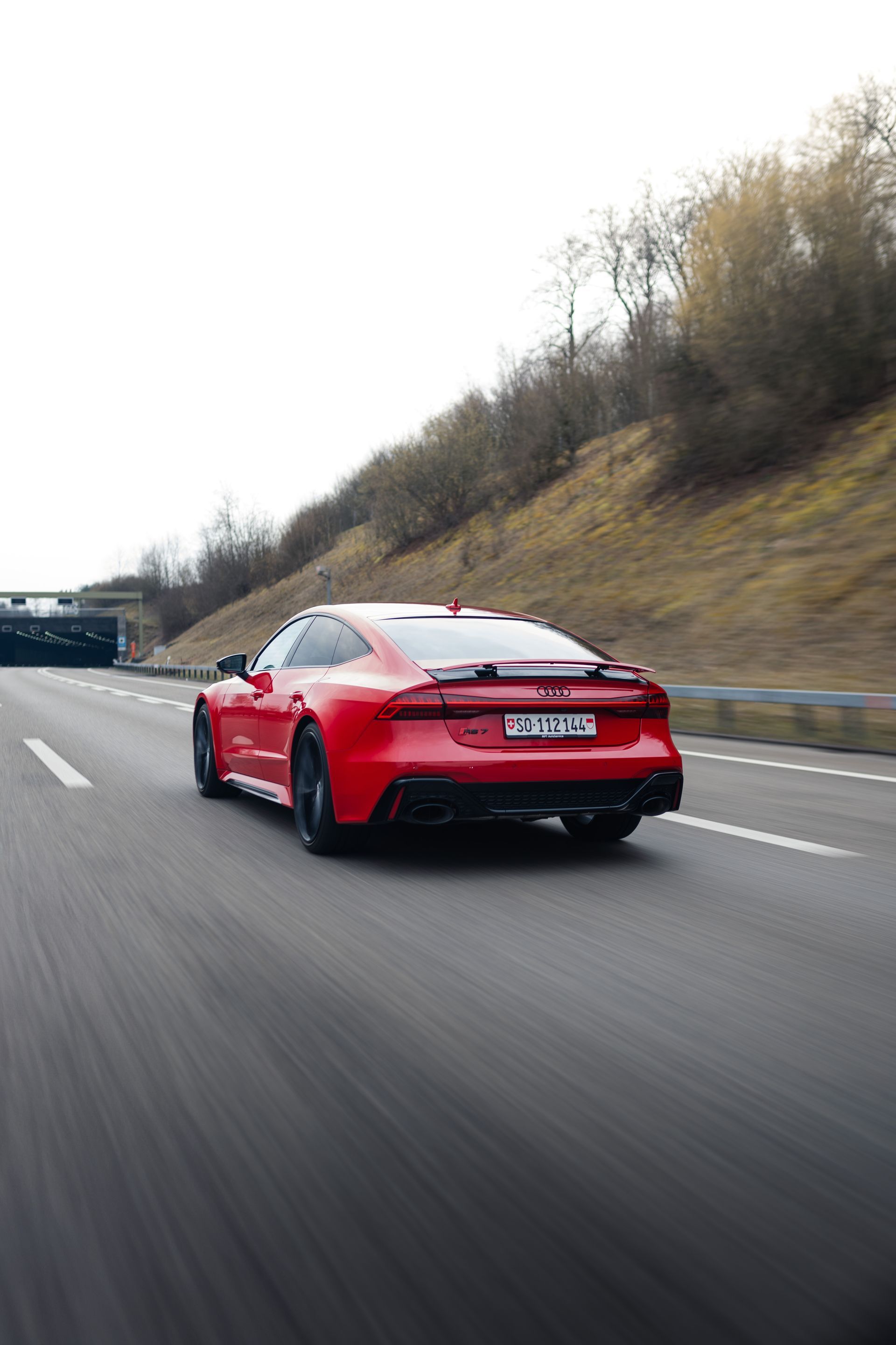 Ein roter Sportwagen fährt auf einer Autobahn.