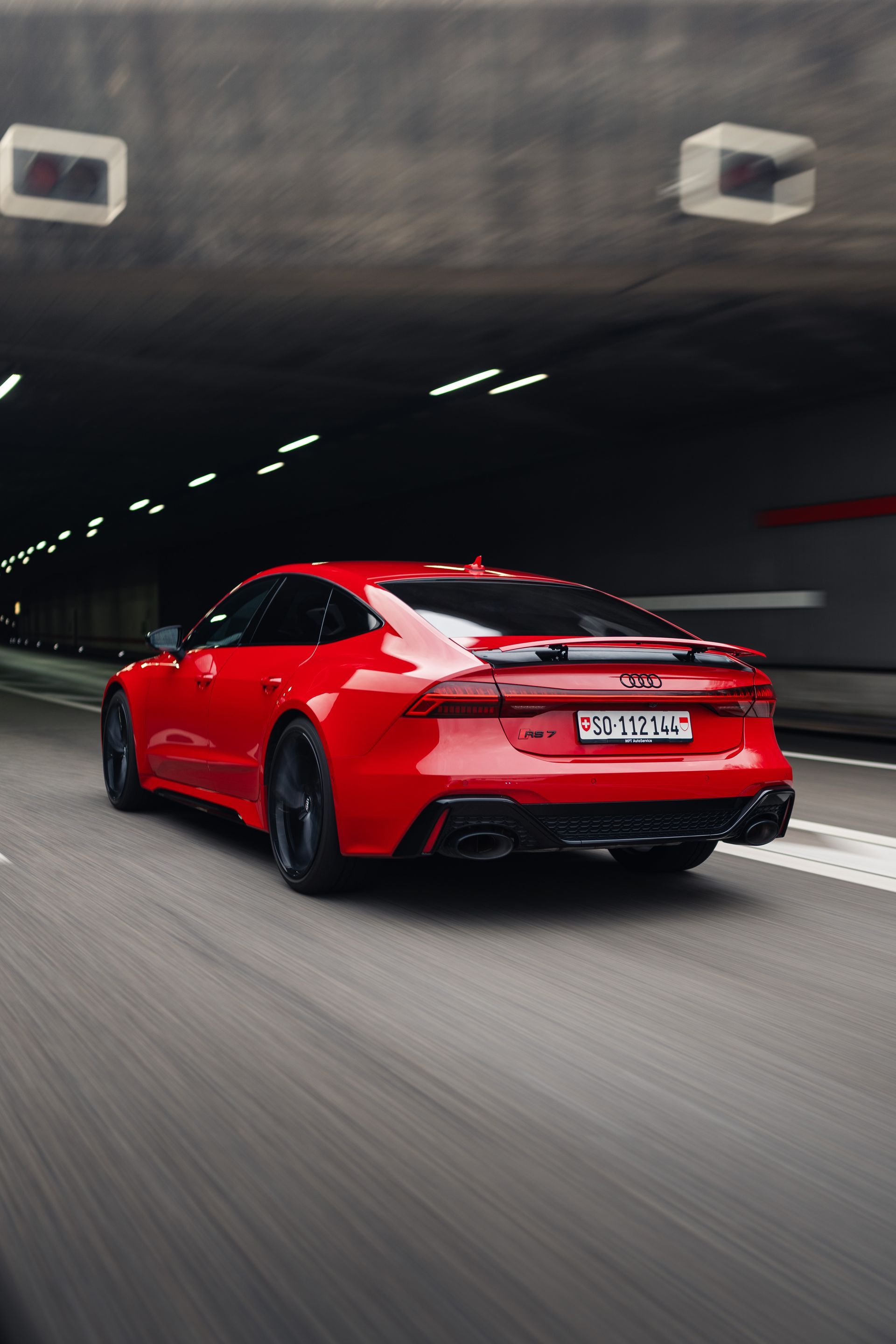 Ein roter Sportwagen fährt durch einen Tunnel.