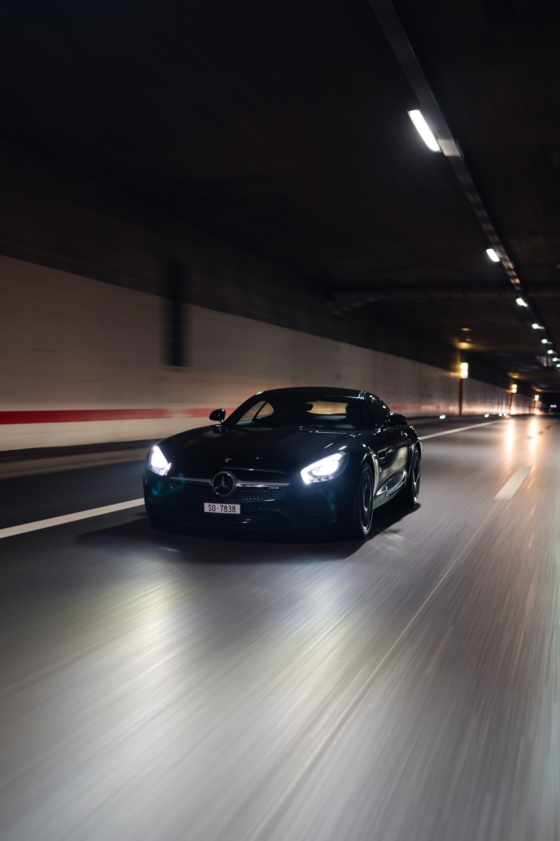 Ein schwarzes Auto fährt nachts durch einen Tunnel.