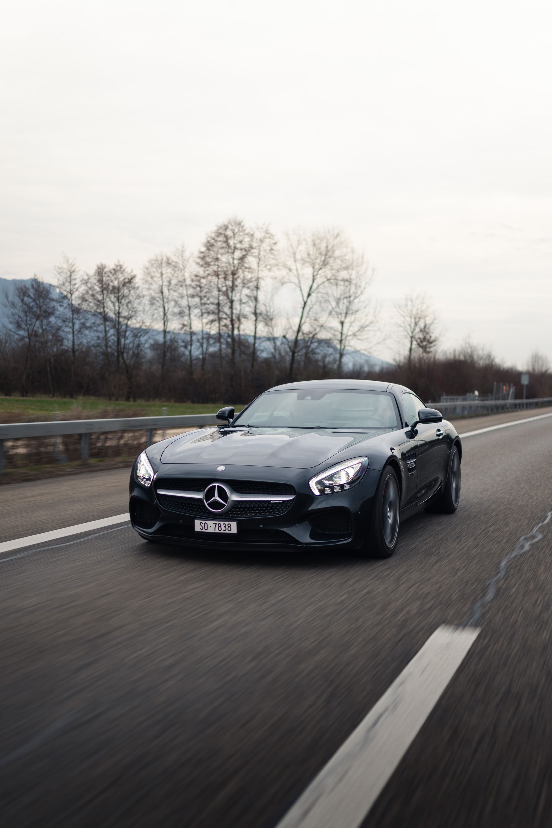 Ein schwarzer Mercedes Benz fährt eine Autobahn entlang.