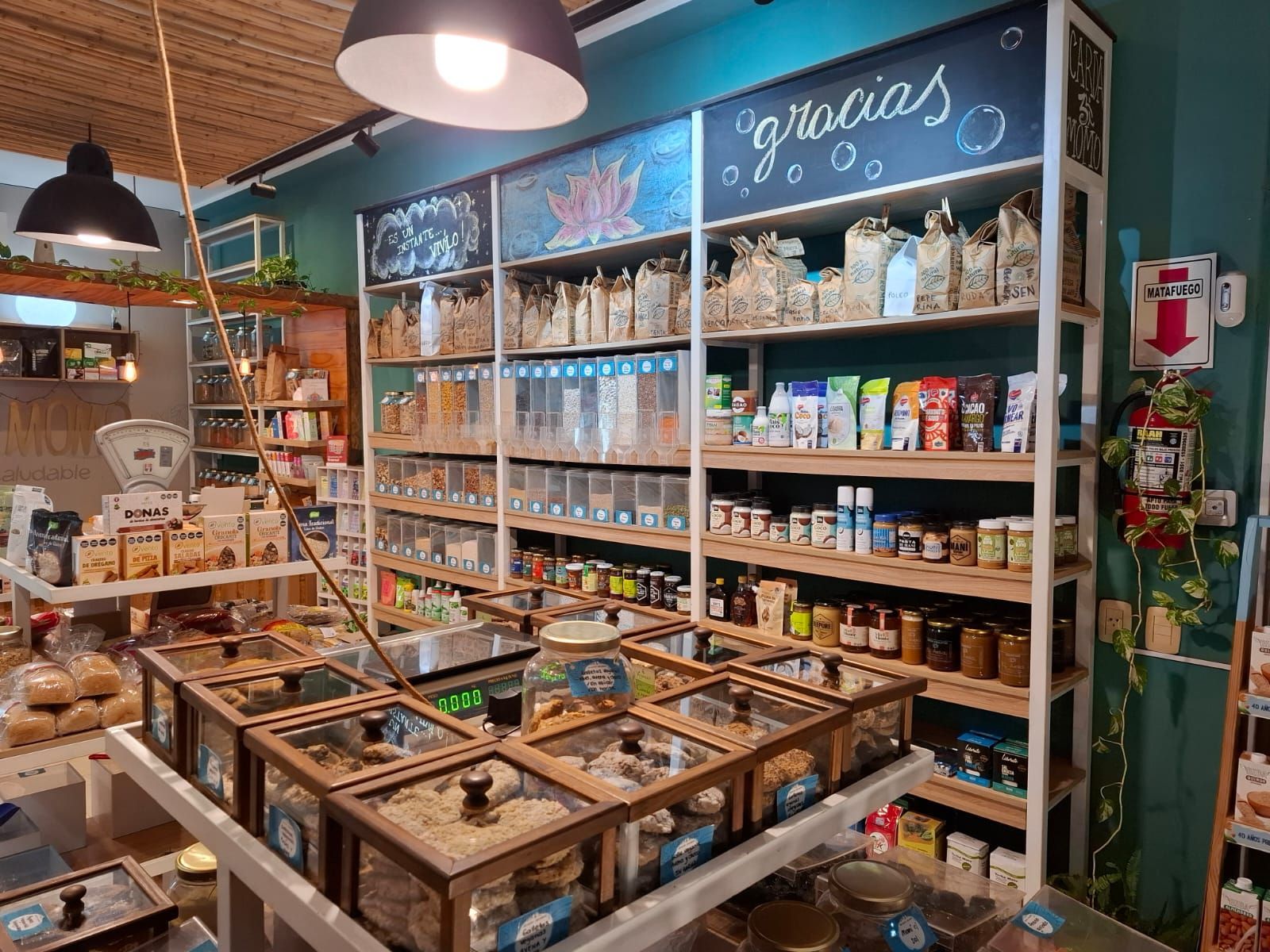 Interior de panadería con expositores de pan, estanterías con productos y cámara frigorífica.