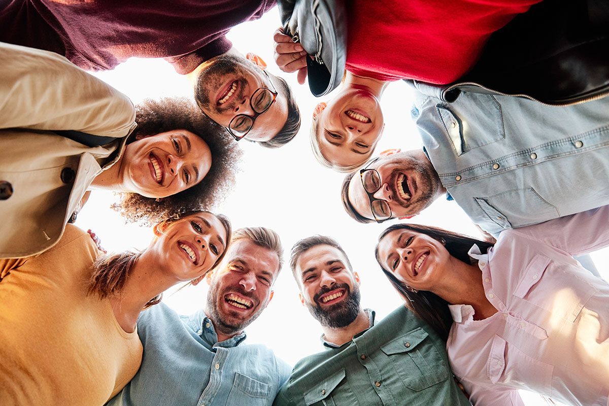 A group of people are standing in a circle and smiling.