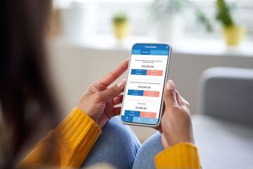 A woman is sitting on a couch using a cell phone.