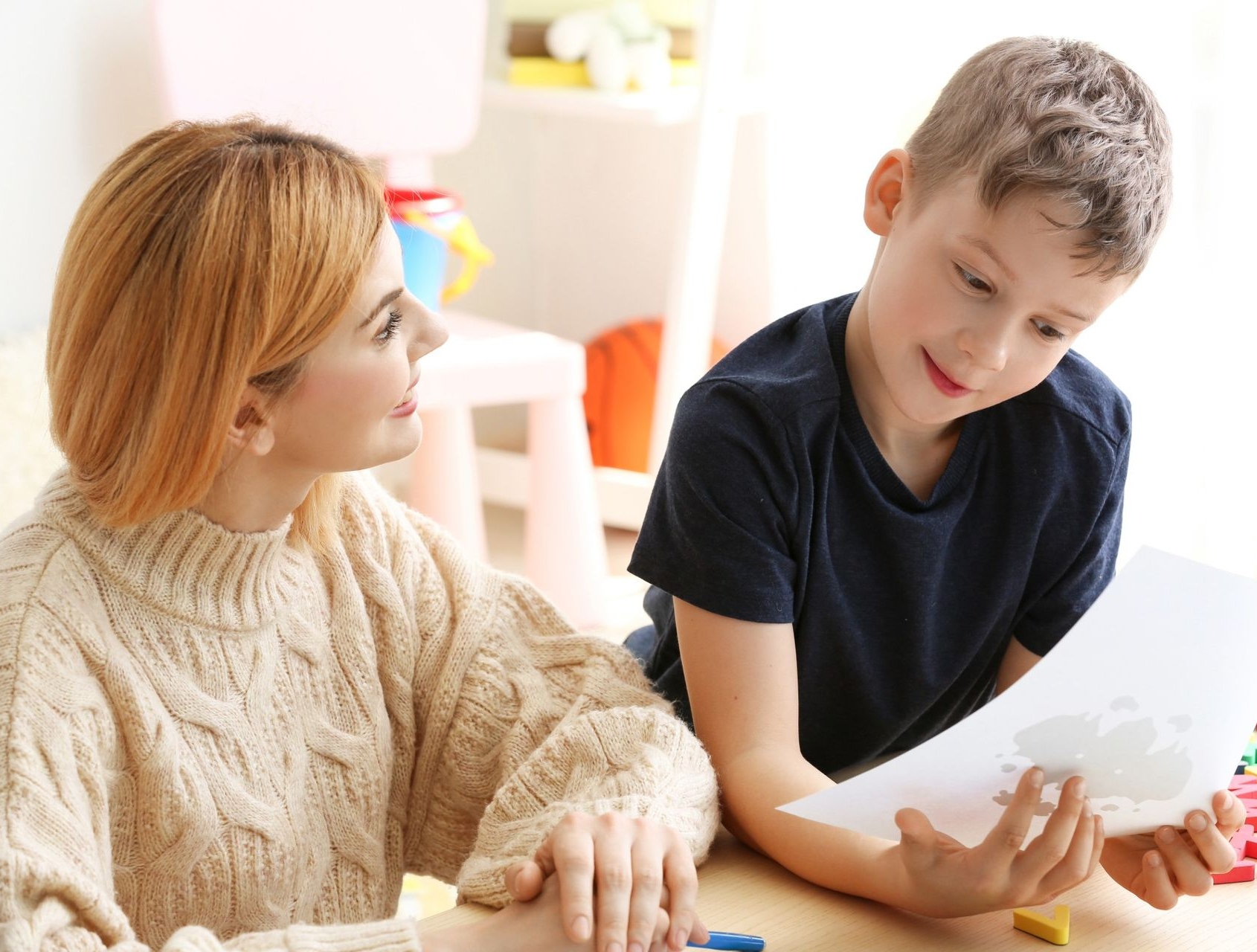 Woman and boy looking at paper, likely in a therapy or learning setting.