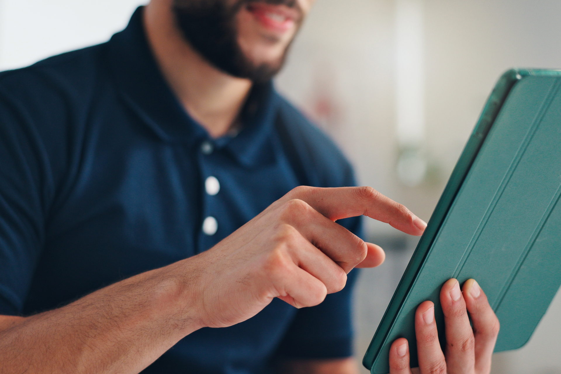 Person pointing at a tablet in a soft-focus indoor setting