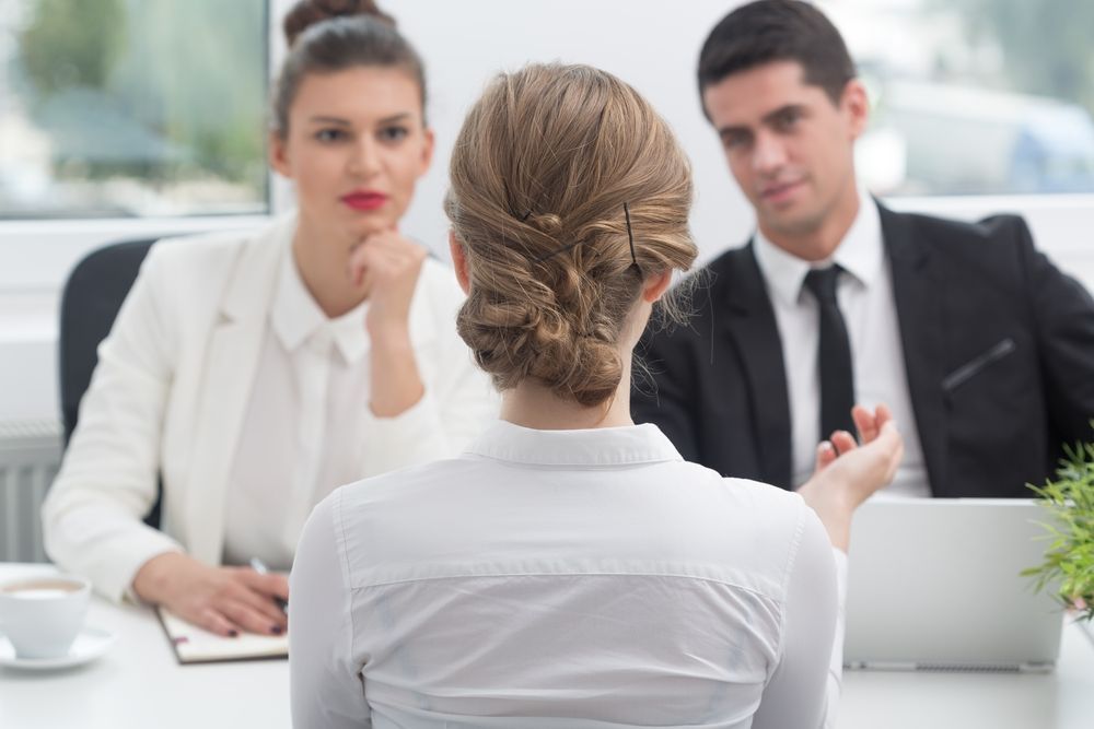 A woman is sitting at a table during a job interview.