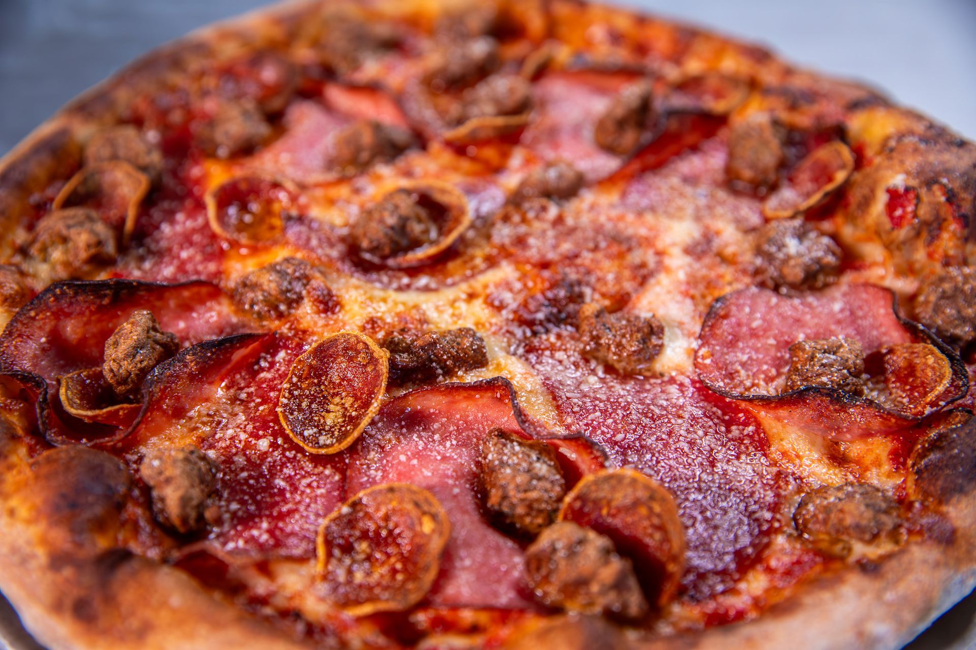 A close up of a pizza with pepperoni and sausage on a table.