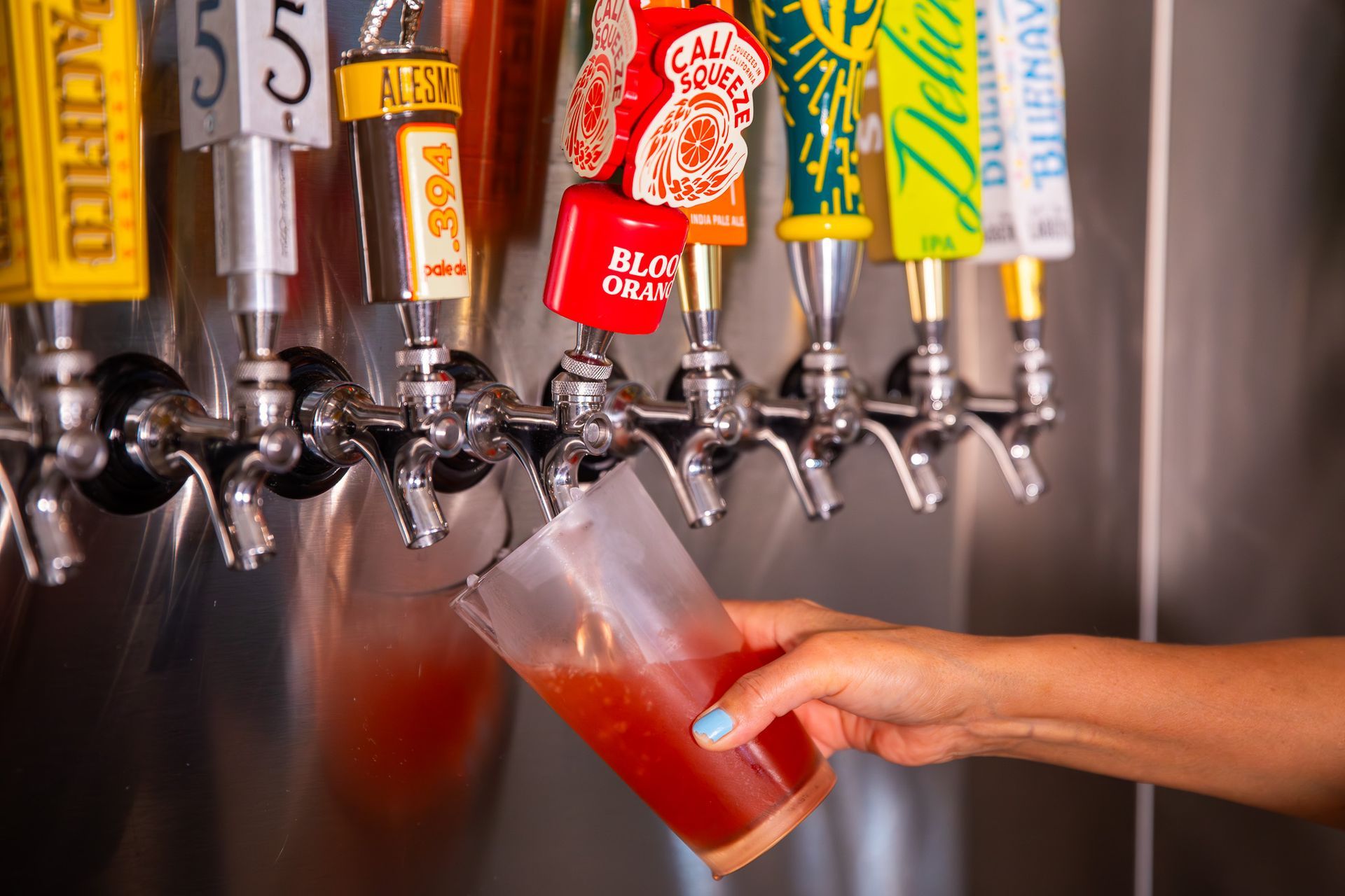 A person is pouring a drink from a tap into a plastic cup.