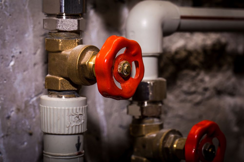 Close-up of plumbing pipes and a red valve.