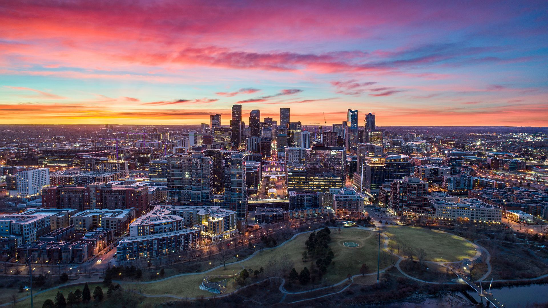 An aerial view of a city at sunset with lots of buildings.