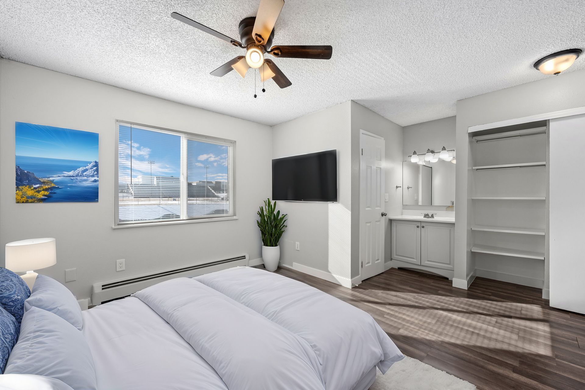  Alternate angle of a photo of a bedroom with built-in shelving in the closet and an area near a bathroom with a vanity mirror