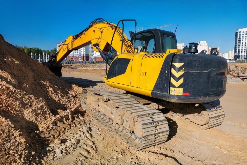 A yellow excavator is digging a pile of dirt on a construction site.