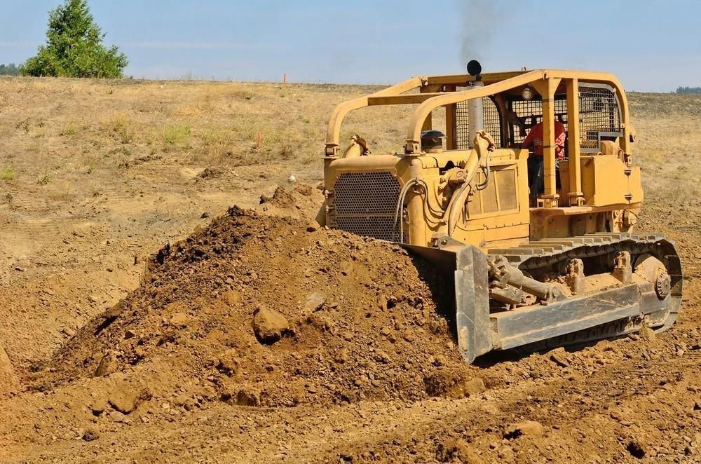 A bulldozer is moving dirt in a field.