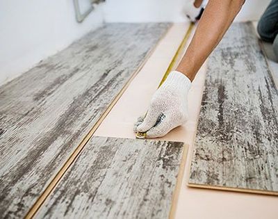 Man measuring and installing wood floor - Floor Installation in Jefferson City, MO