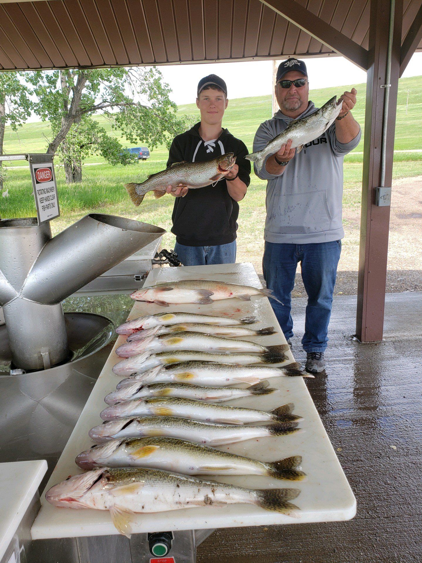 Two men are standing next to a table full of fish.