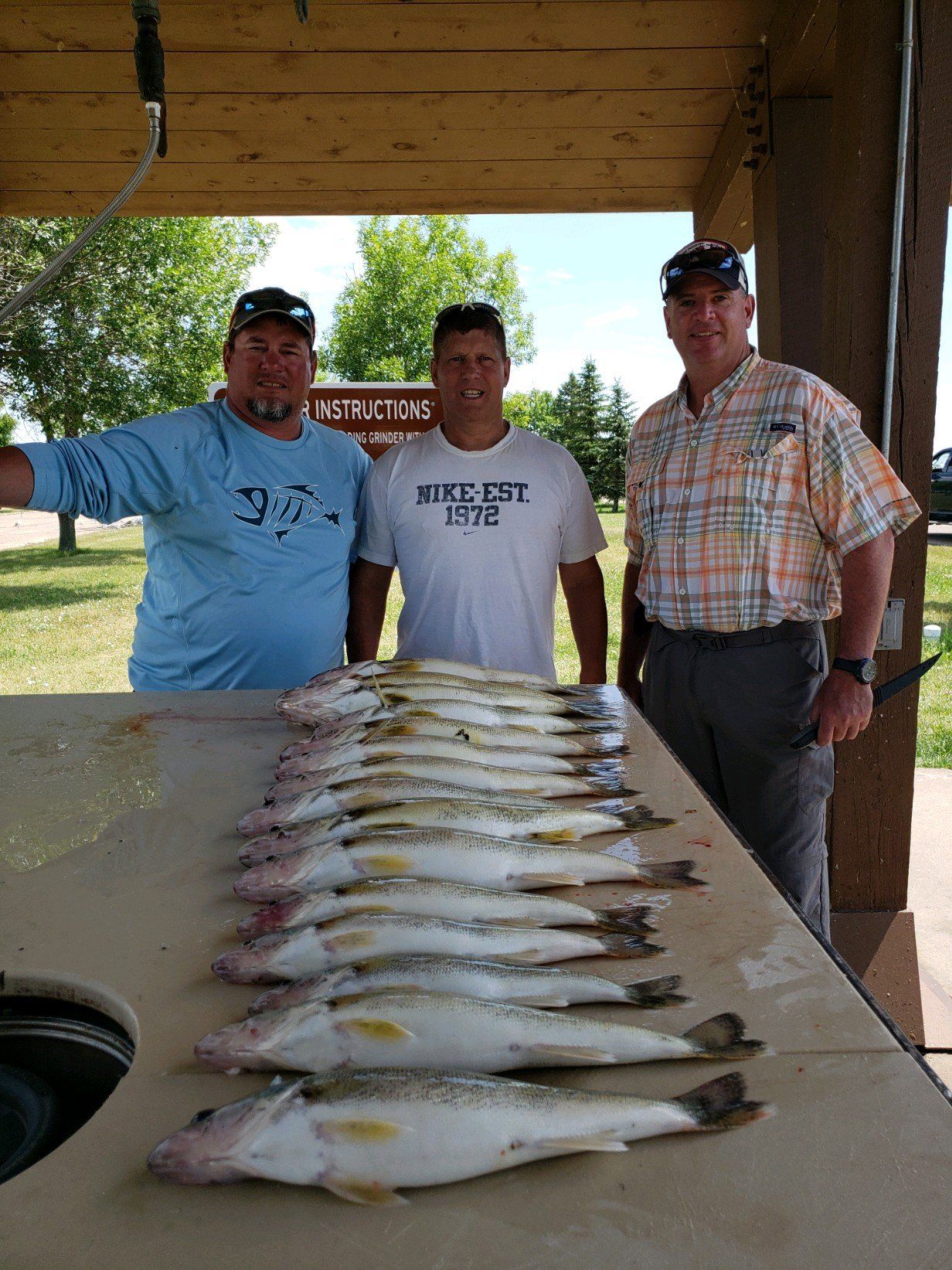 Three men are standing next to a table full of fish.