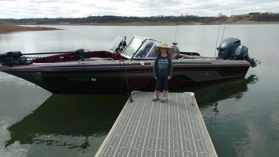 A woman is standing on a dock next to a boat.