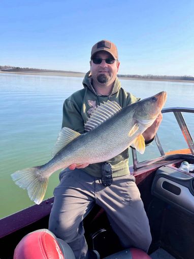 A man is sitting on a boat holding a large fish.