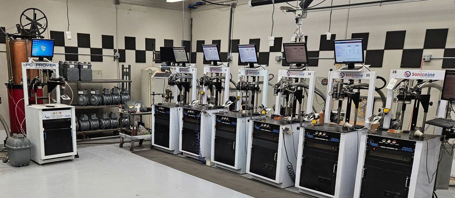 A row of sonic nozzle provers with computer screens and gas meters