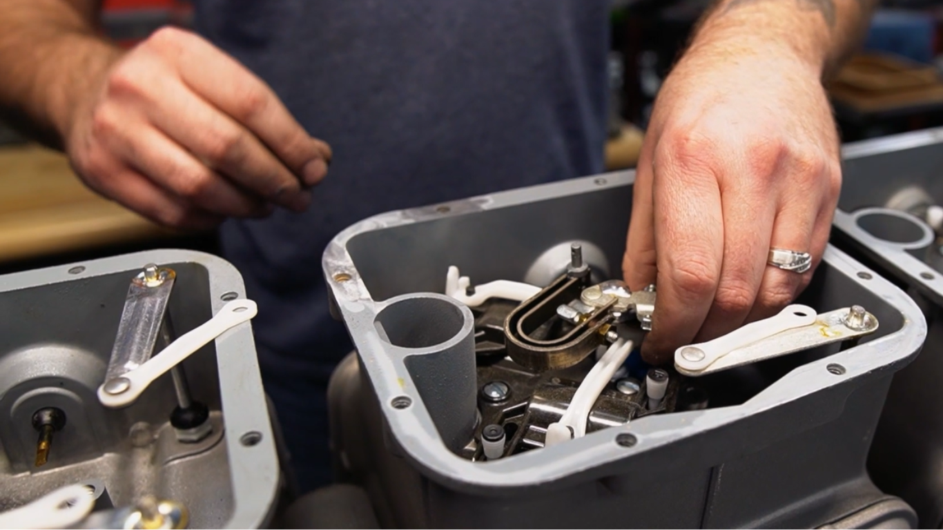 Hands working on the internal components of a gas meter. The person is assembling small parts.