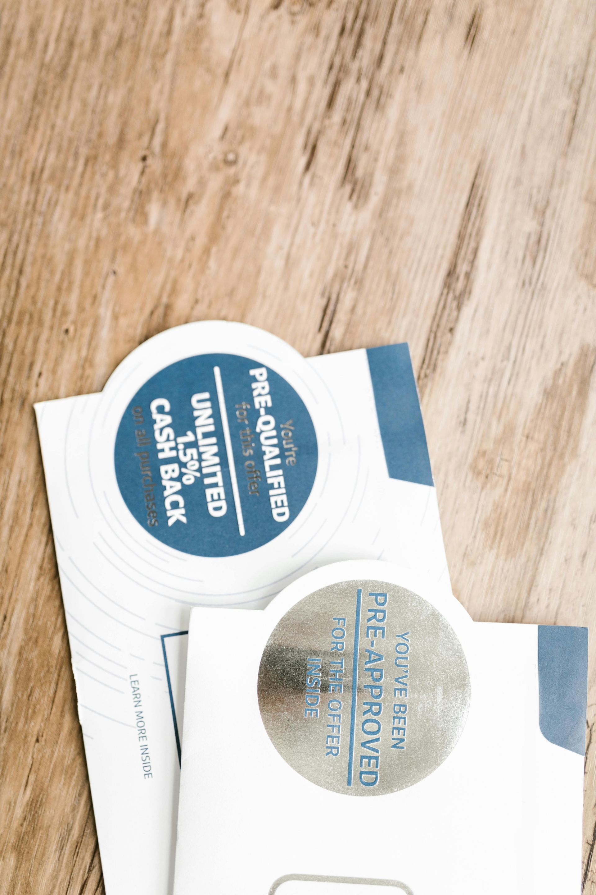 Two white envelopes with blue accents and pre-approval stickers on a wooden surface.
