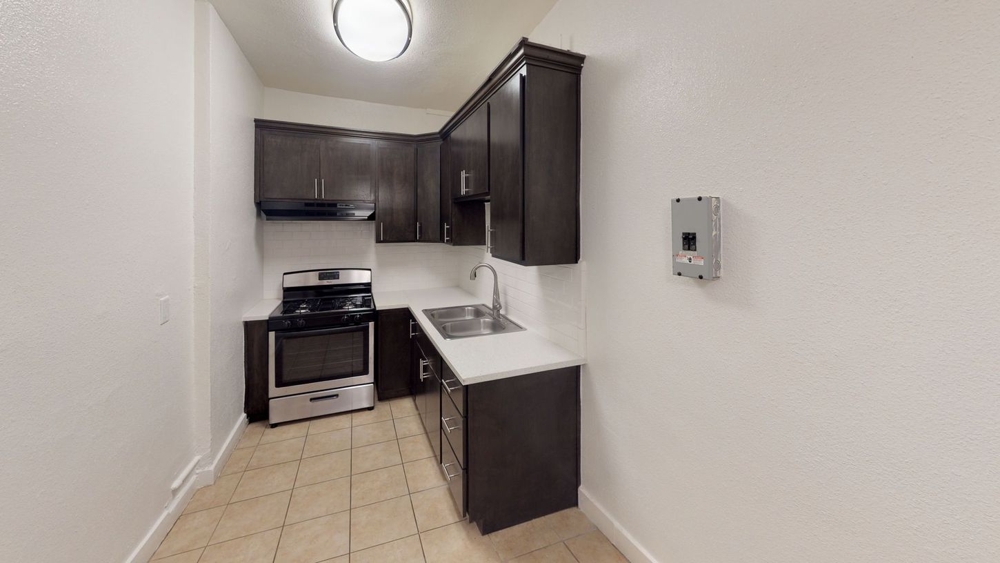 Small kitchen with dark cabinets, stainless steel appliances, and white countertops.