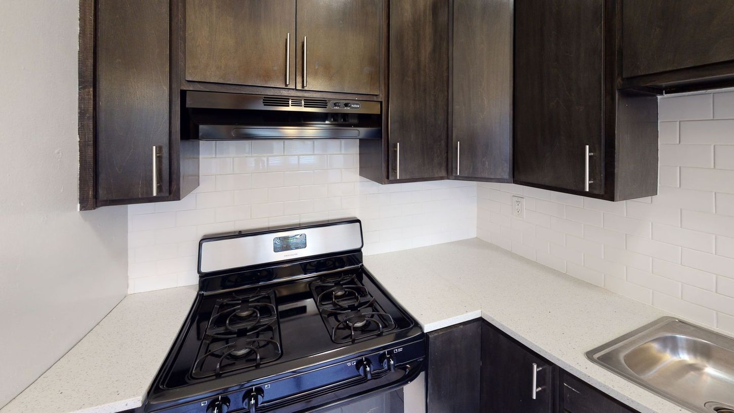 Kitchen with dark cabinets, white countertops, and stainless steel appliances.