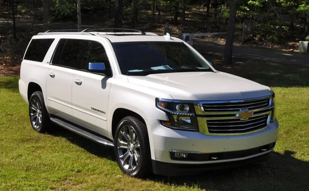 A white Chevrolet Suburban SUV parked on a grassy lawn.