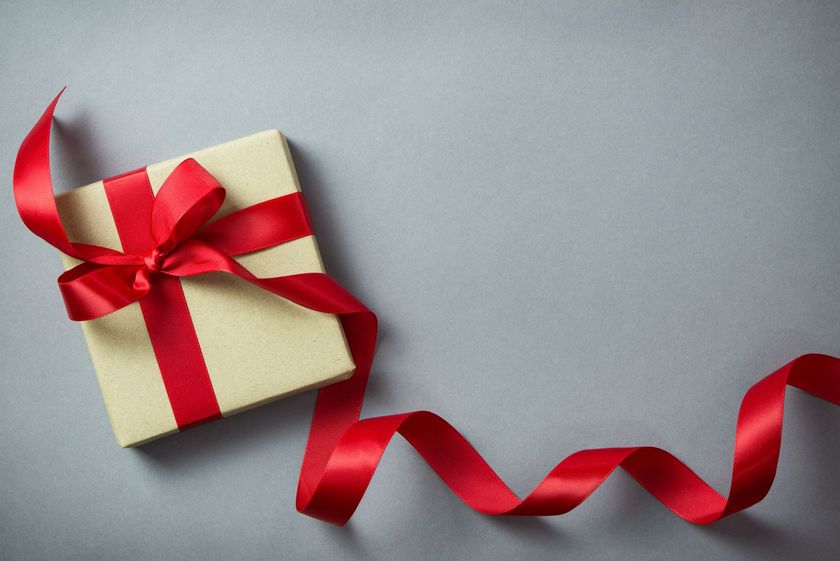 A gift box with a red ribbon and bow on a gray background.