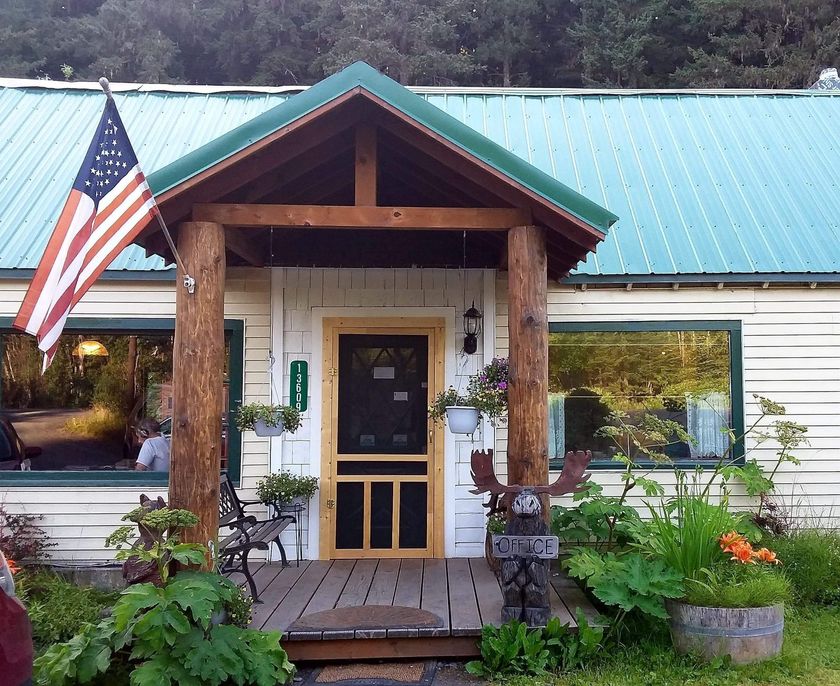 Rustic cabin interior with fireplace, dining table, and wooden walls.