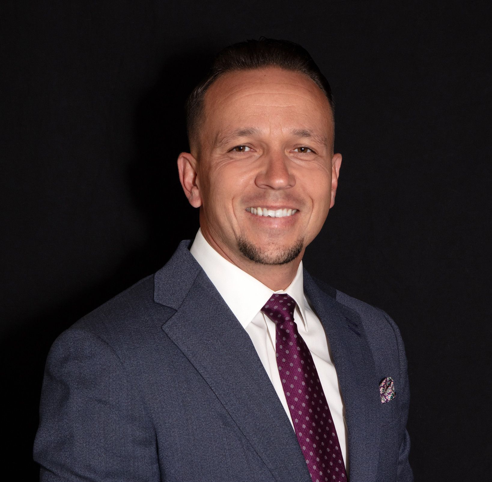 A man in a suit and tie is smiling for the camera.
