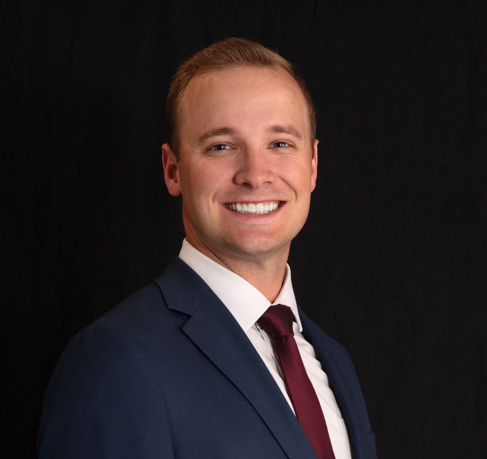 A man in a suit and tie is smiling for the camera.