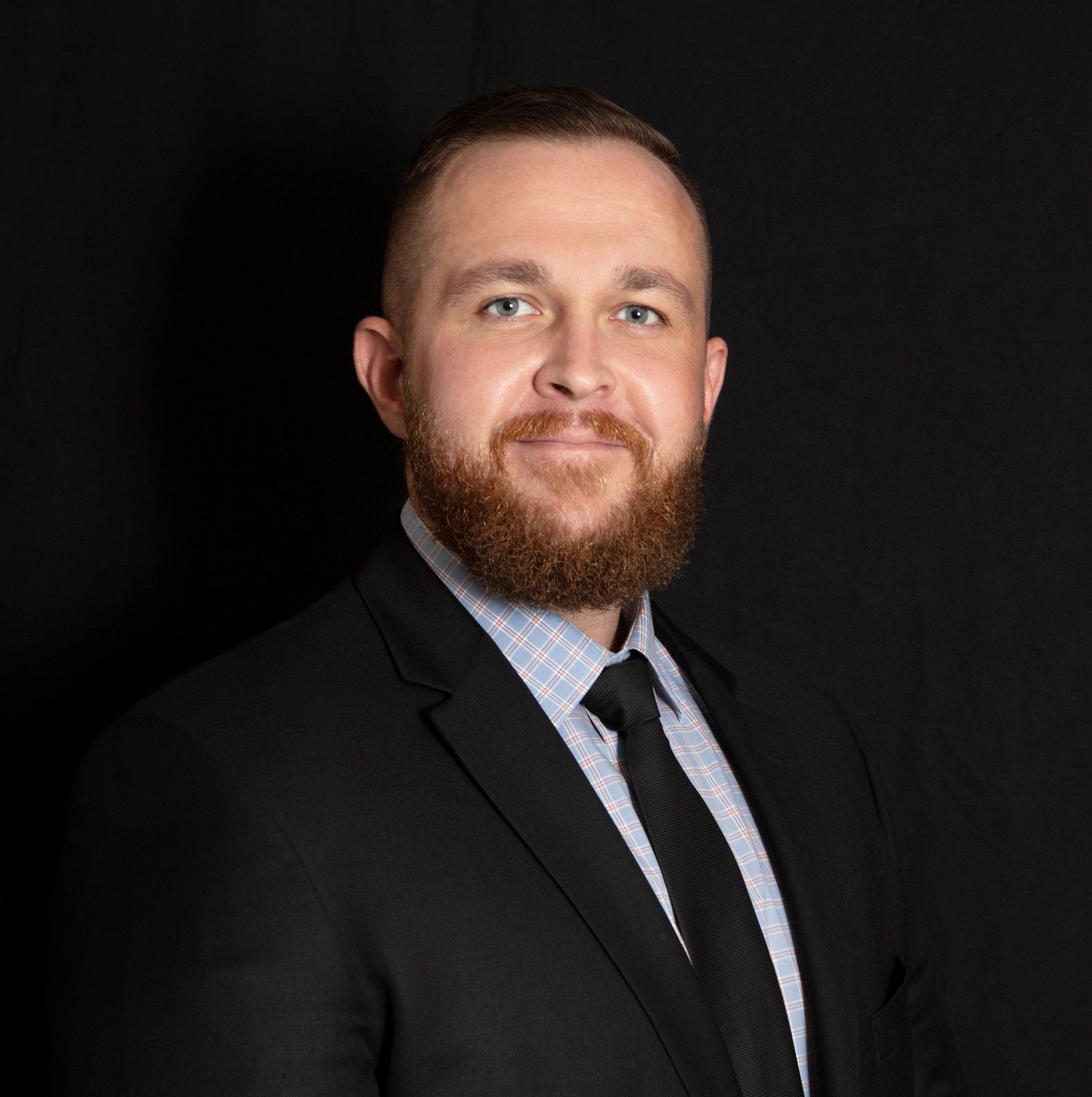 A man with a beard is wearing a suit and tie.