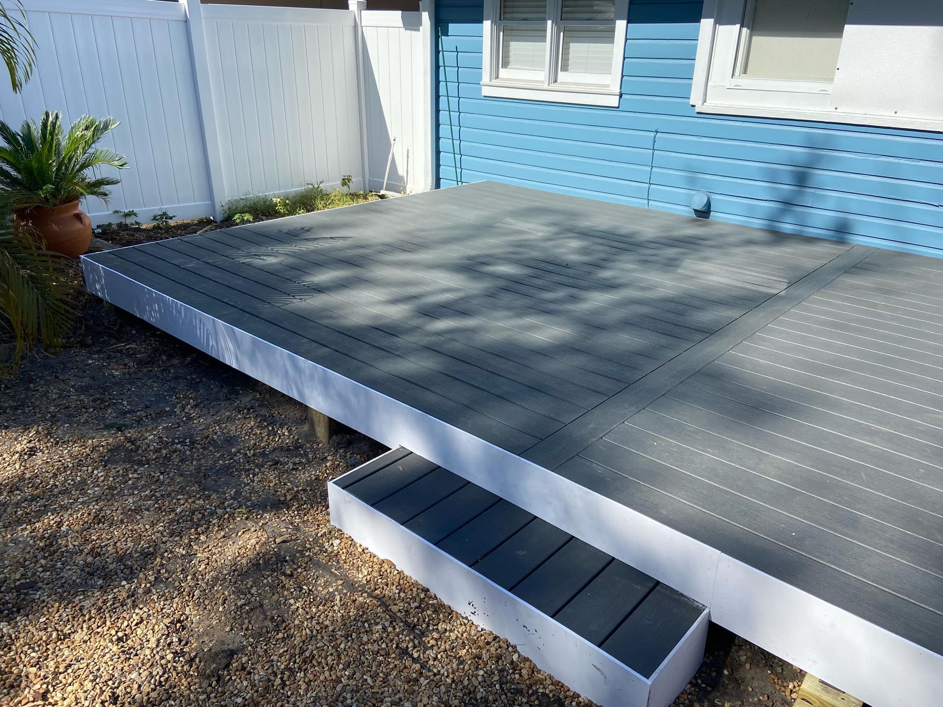 A blue house with a gray deck in front of it