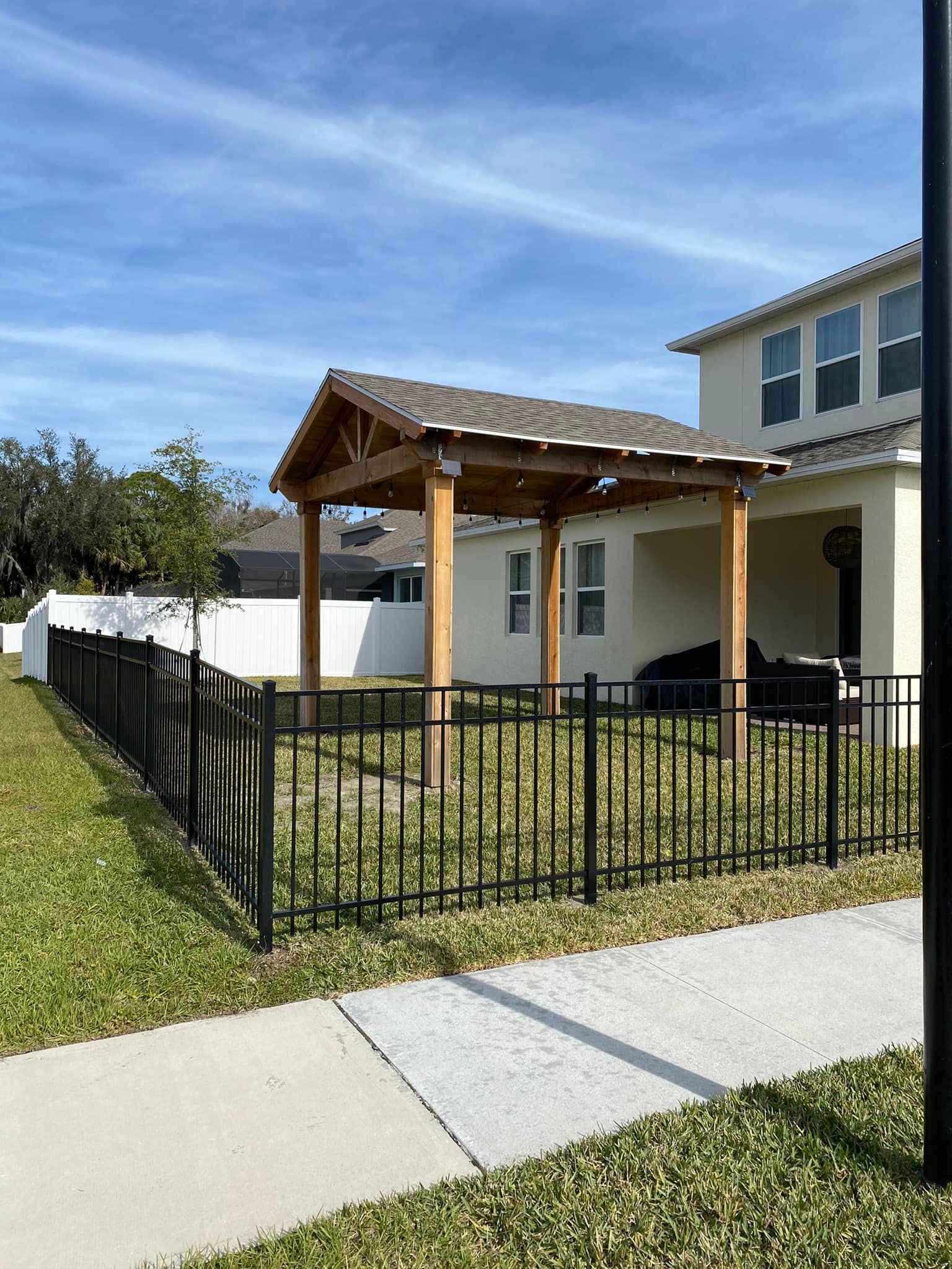 A house with a pergola and a fence around it.
