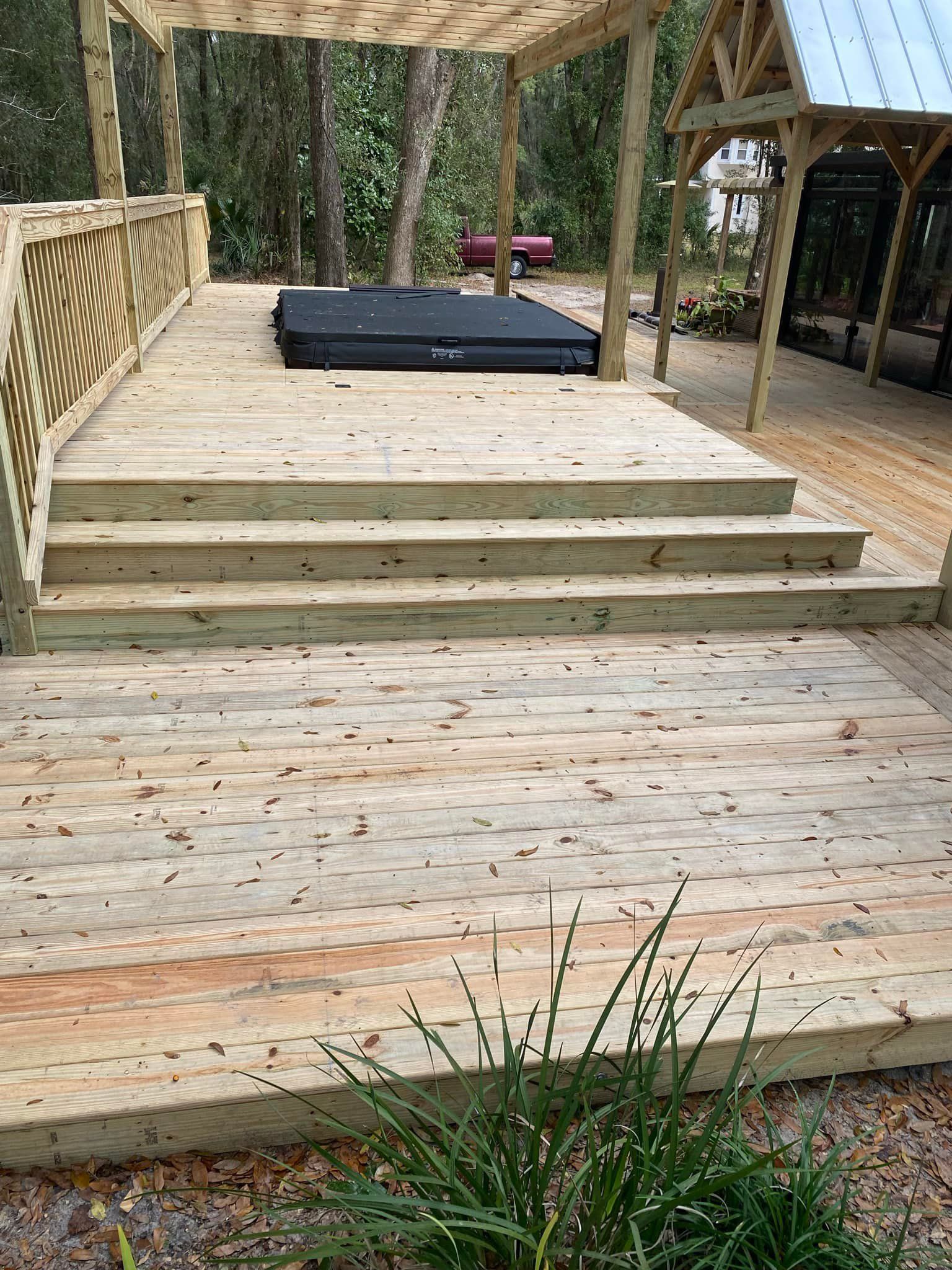 A wooden deck with stairs and a hot tub under a pergola.